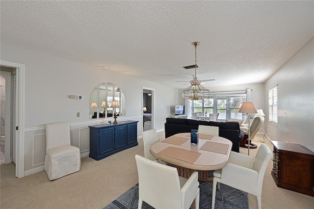 dining area featuring light carpet, a textured ceiling, and ceiling fan