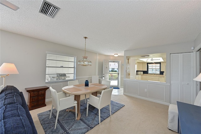 carpeted dining space with a textured ceiling and ceiling fan