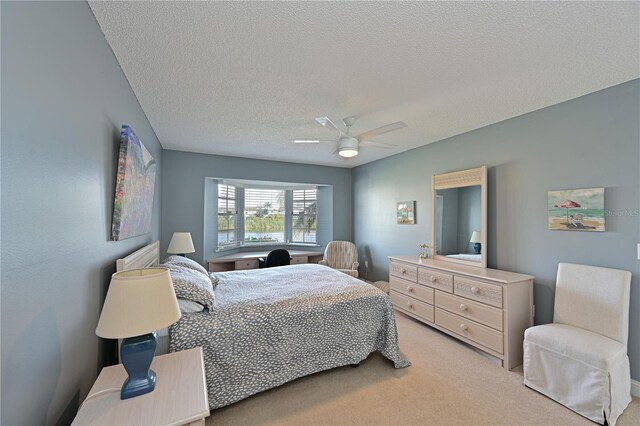 bedroom with ceiling fan, a textured ceiling, and light carpet