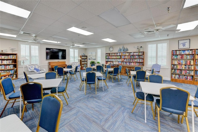 carpeted dining space featuring a drop ceiling and ceiling fan