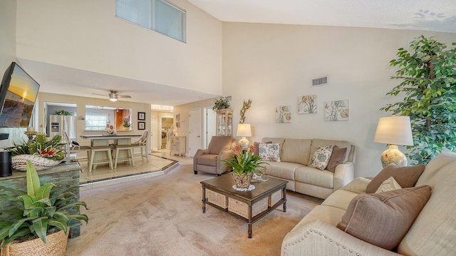 carpeted living room featuring ceiling fan and a towering ceiling