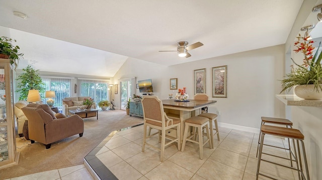 dining space with ceiling fan, light tile patterned floors, and vaulted ceiling