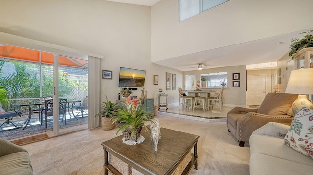 living room featuring a wealth of natural light, ceiling fan, and light colored carpet