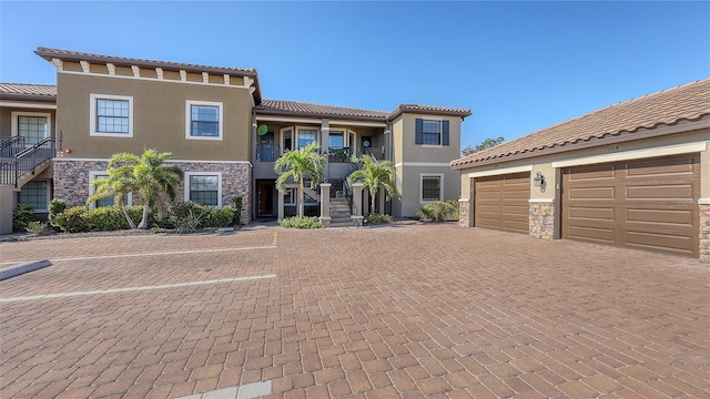 view of front of home featuring a garage, stone siding, decorative driveway, and stucco siding