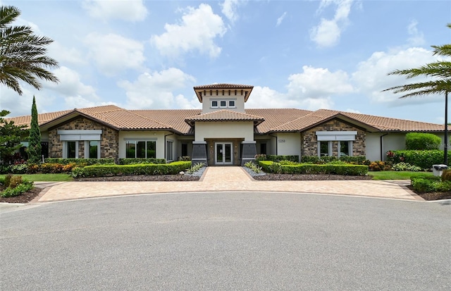 view of front of home with stone siding, a tile roof, and stucco siding