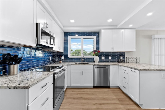 kitchen with white cabinetry, kitchen peninsula, stainless steel appliances, light hardwood / wood-style flooring, and sink