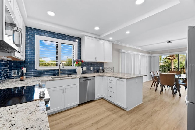 kitchen featuring decorative light fixtures, sink, stainless steel appliances, and white cabinetry