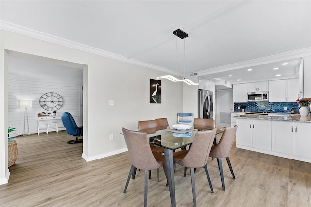 dining space with ornamental molding and light hardwood / wood-style flooring