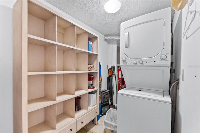 laundry room with a textured ceiling and stacked washer / dryer