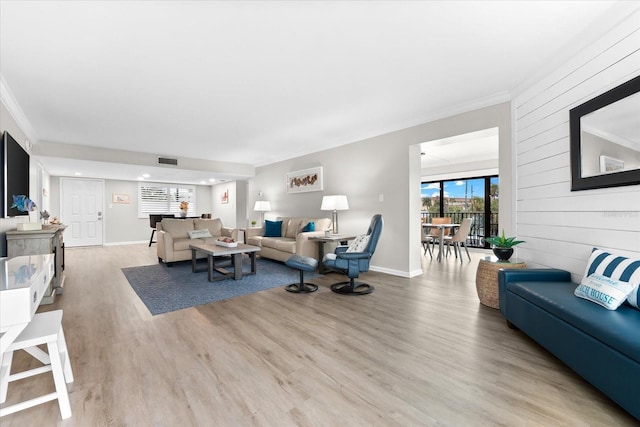 living room featuring wood walls, crown molding, and light hardwood / wood-style flooring