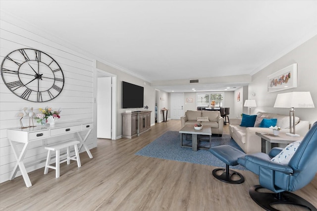 living room with ornamental molding and light hardwood / wood-style flooring