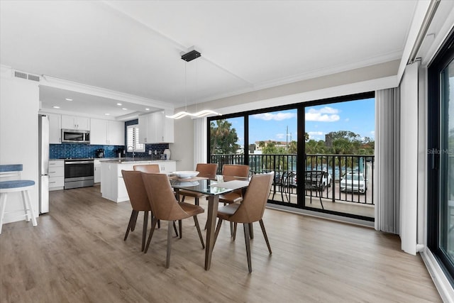 dining space with crown molding, a healthy amount of sunlight, and light hardwood / wood-style floors