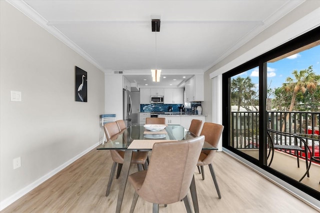 dining space featuring light hardwood / wood-style floors, sink, and crown molding