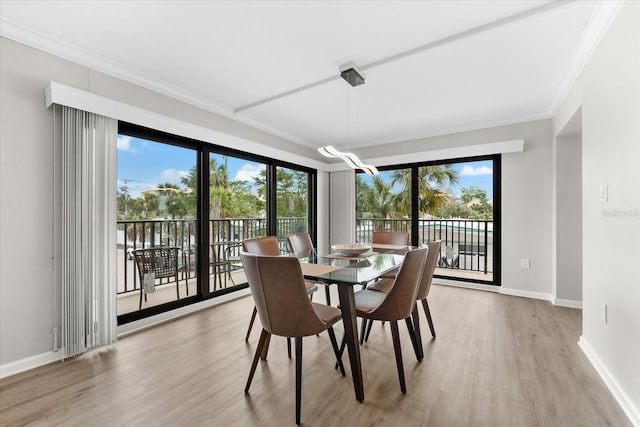 dining space with light wood-type flooring, crown molding, and plenty of natural light