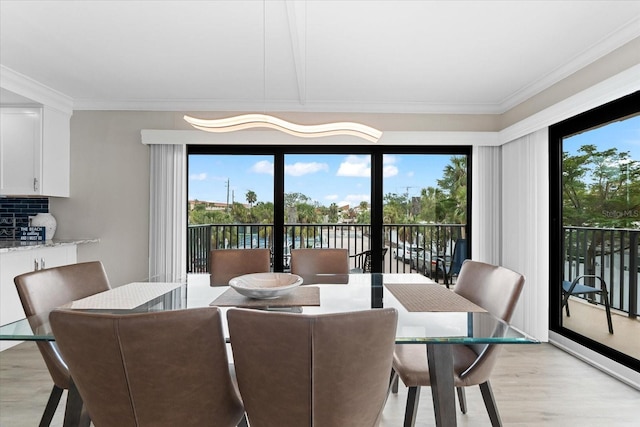 dining area with light wood-type flooring, a wealth of natural light, and ornamental molding