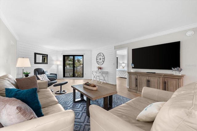 living room featuring wooden walls, ornamental molding, and light wood-type flooring