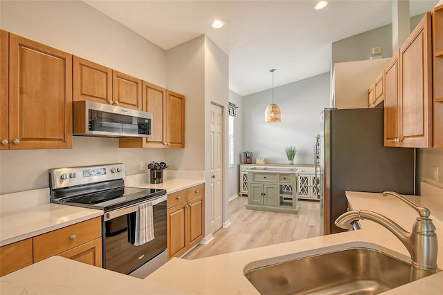 kitchen with appliances with stainless steel finishes, light wood-type flooring, vaulted ceiling, sink, and decorative light fixtures