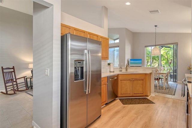 kitchen featuring kitchen peninsula, appliances with stainless steel finishes, sink, pendant lighting, and lofted ceiling