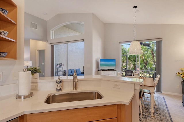 kitchen with decorative light fixtures, lofted ceiling, sink, and light tile patterned floors