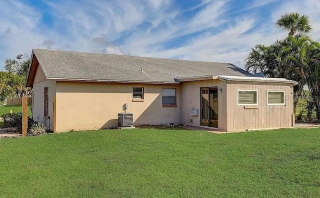 back of house featuring central AC unit and a lawn