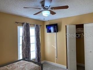 unfurnished bedroom with carpet, ceiling fan, a textured ceiling, and a closet