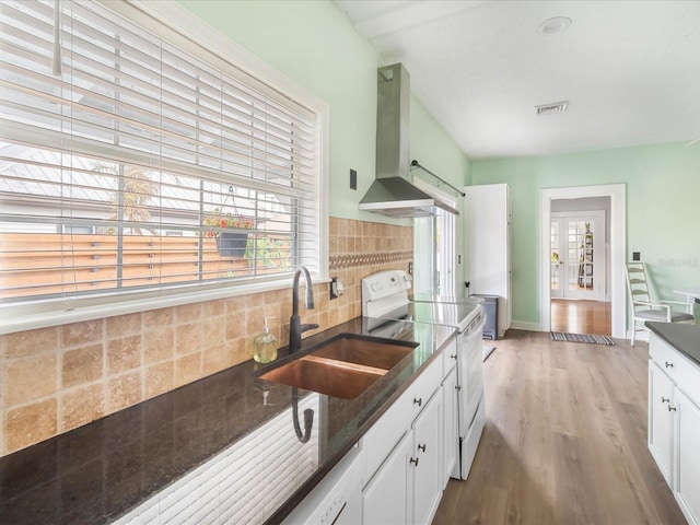 kitchen with sink, white electric range oven, tasteful backsplash, island exhaust hood, and white cabinets