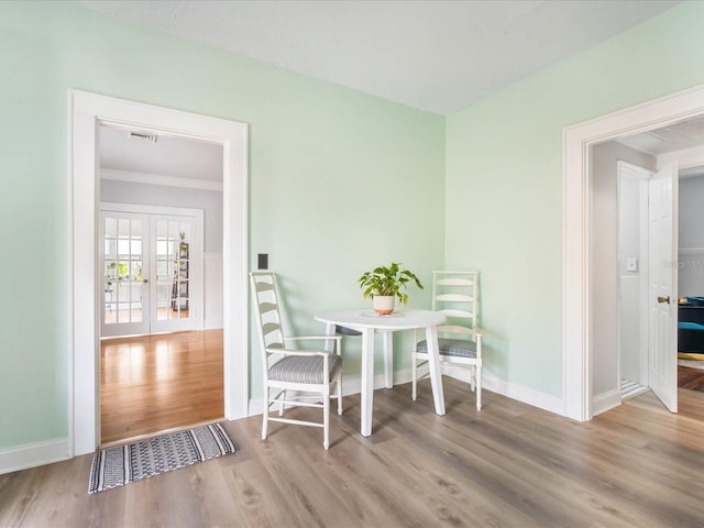 dining area with french doors, light hardwood / wood-style floors, and ornamental molding