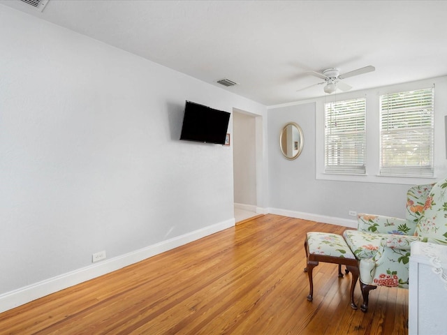 living area featuring hardwood / wood-style floors and ceiling fan