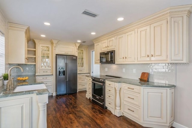 kitchen featuring dark stone counters, sink, appliances with stainless steel finishes, cream cabinetry, and dark hardwood / wood-style flooring