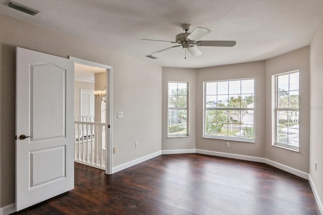 unfurnished room featuring a textured ceiling, ceiling fan with notable chandelier, and dark wood-type flooring