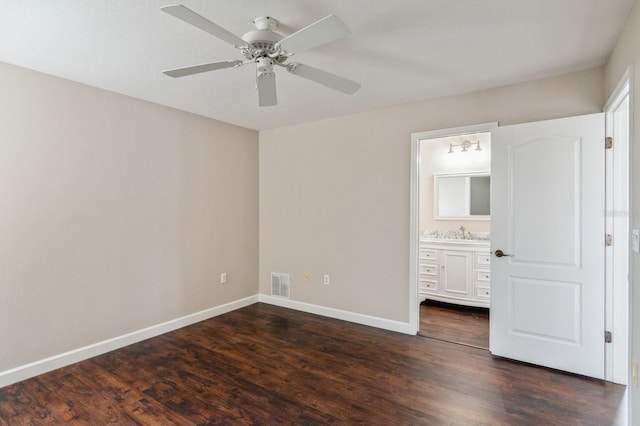 unfurnished bedroom featuring ensuite bath, ceiling fan, dark wood-type flooring, and sink