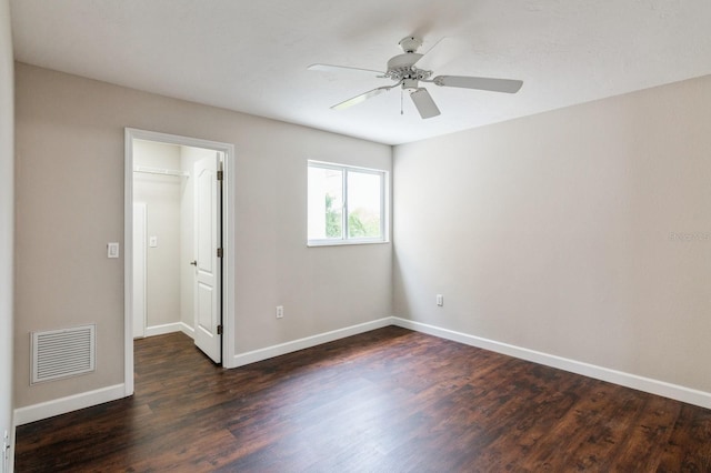 unfurnished bedroom with ceiling fan, dark hardwood / wood-style flooring, a walk in closet, and a closet