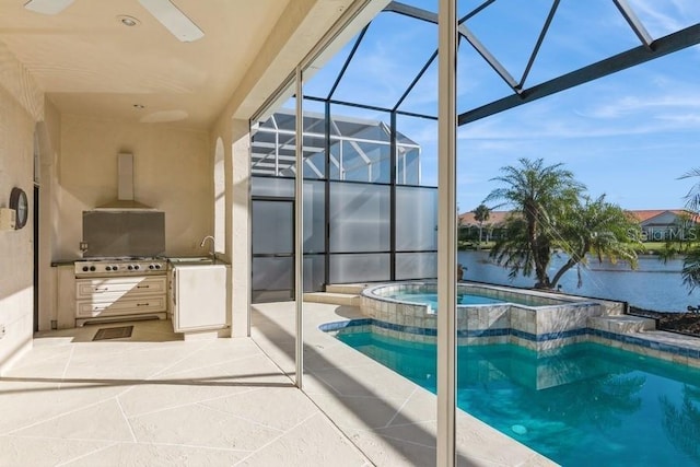 view of pool with an in ground hot tub, a water view, a patio, and an outdoor kitchen