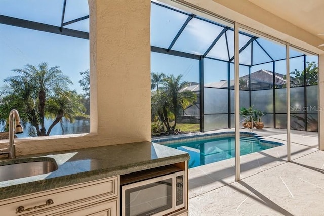 view of swimming pool with a patio, a water view, glass enclosure, and sink