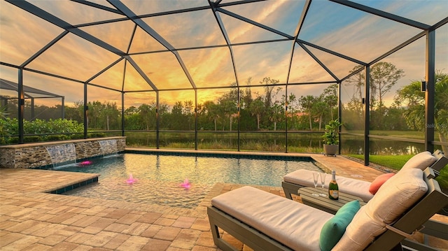 pool at dusk with pool water feature and a patio area