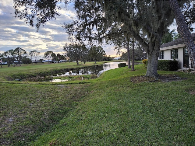 yard at dusk featuring a water view