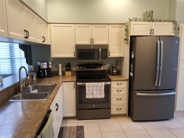 kitchen featuring white cabinets, appliances with stainless steel finishes, light tile patterned flooring, and sink