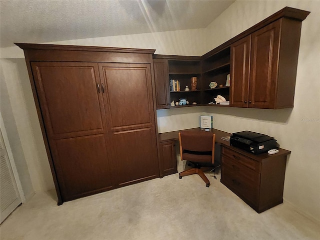 office space featuring a textured ceiling, built in desk, and light carpet