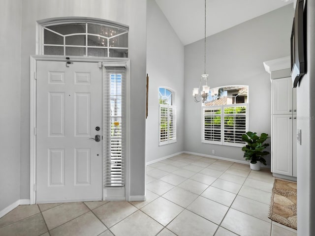 tiled entryway with high vaulted ceiling and an inviting chandelier