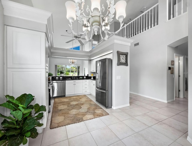 kitchen with a high ceiling, ceiling fan with notable chandelier, sink, light tile patterned floors, and stainless steel appliances