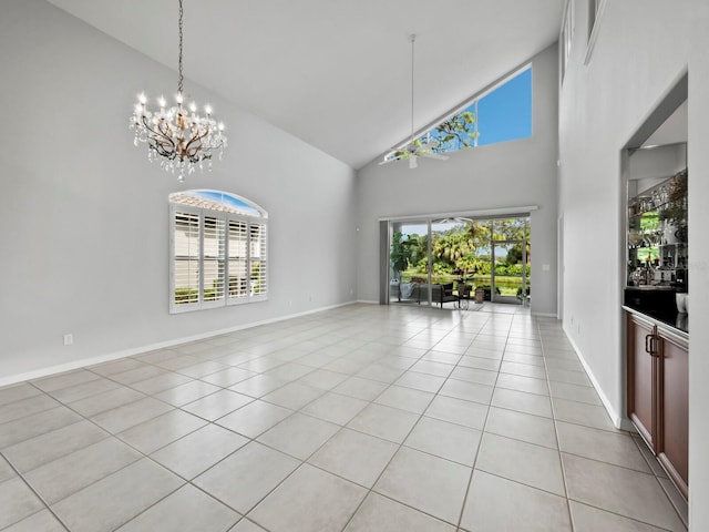 unfurnished living room with high vaulted ceiling, a chandelier, and light tile patterned floors