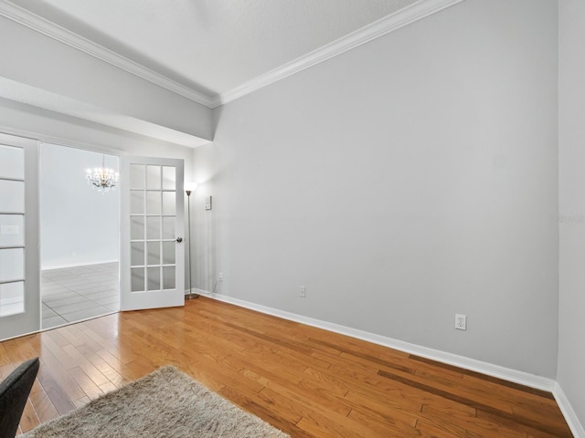 spare room featuring a chandelier, crown molding, french doors, and wood-type flooring