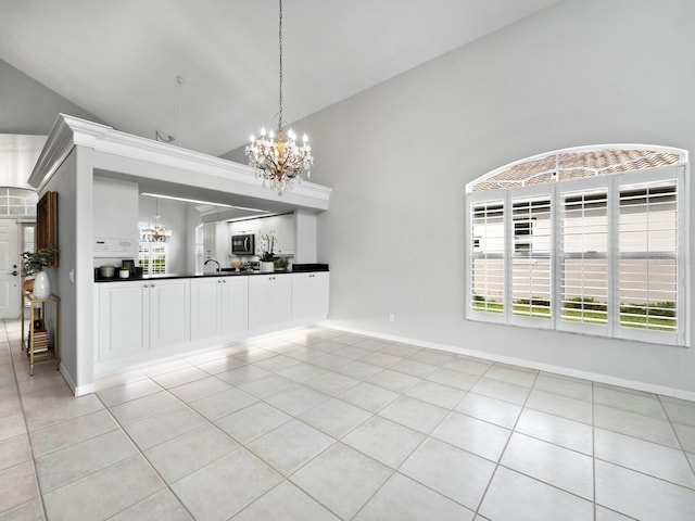 unfurnished dining area with a notable chandelier, light tile patterned floors, sink, and high vaulted ceiling