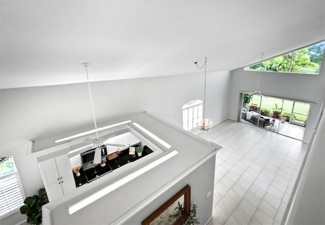 living room with ceiling fan with notable chandelier and high vaulted ceiling