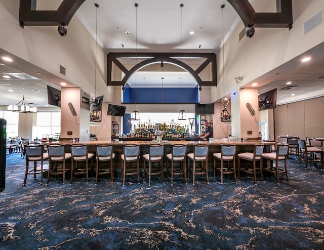 bar with crown molding and a high ceiling