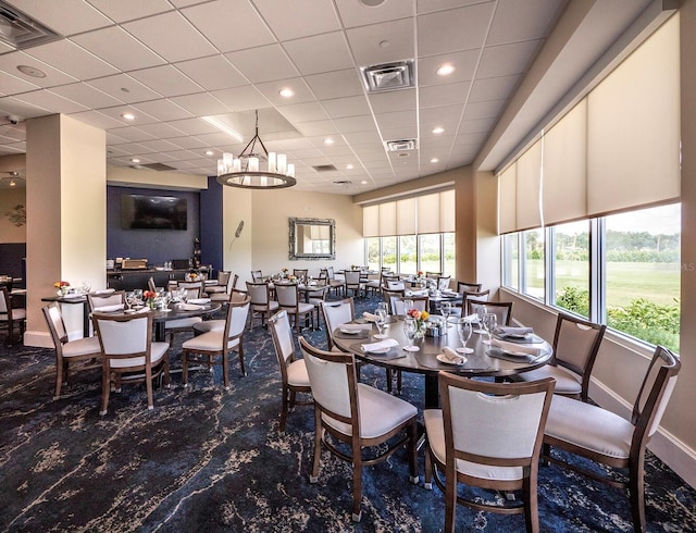 dining space featuring a drop ceiling and a notable chandelier