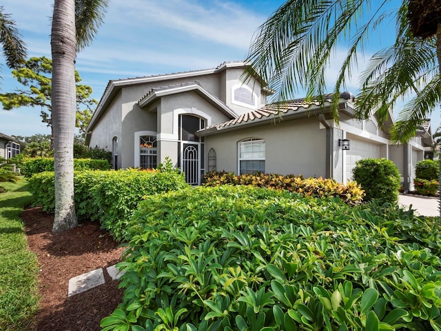 view of front of house featuring a tile roof, a garage, and stucco siding