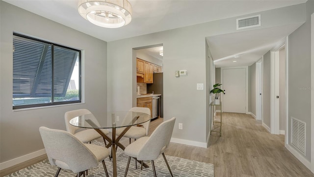 dining room with light hardwood / wood-style floors and a notable chandelier