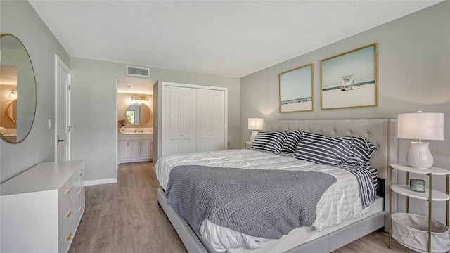 bedroom featuring light hardwood / wood-style flooring, ensuite bath, and a closet