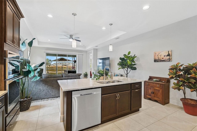 kitchen with ceiling fan, sink, stainless steel appliances, a raised ceiling, and a center island with sink